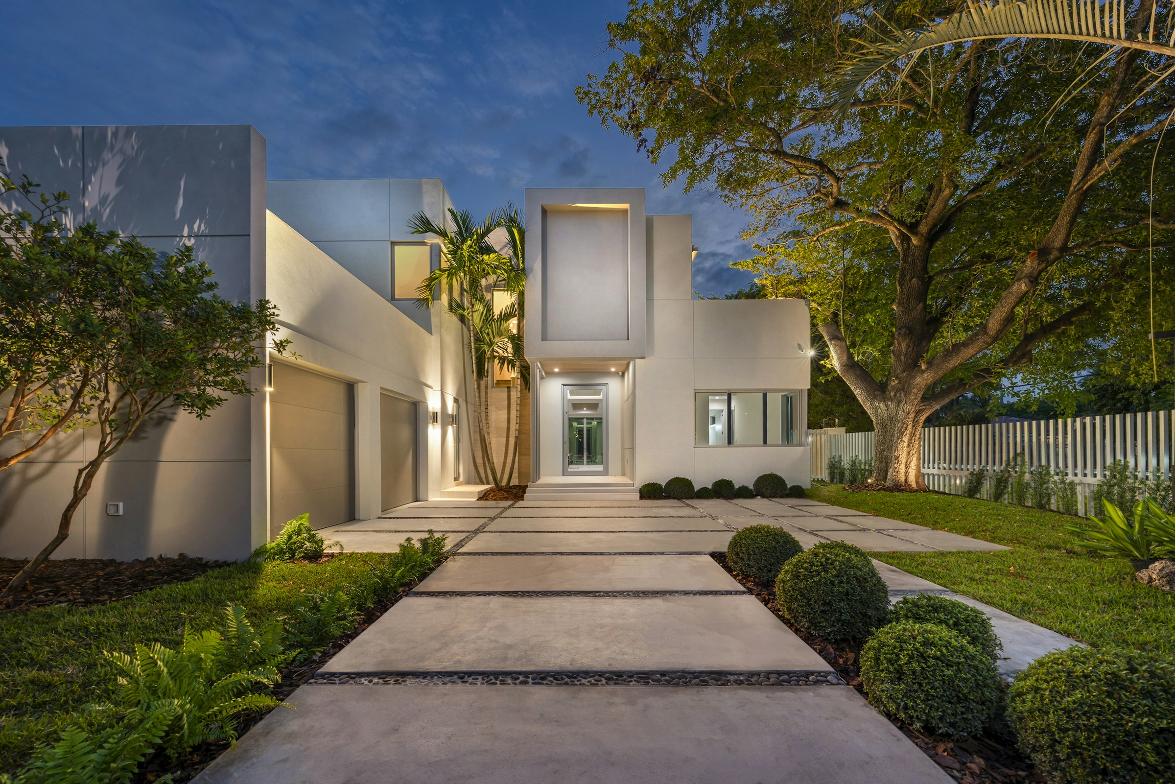 Modern home exterior with illuminated entry at dusk